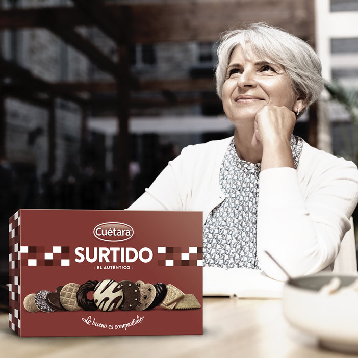 Fotografía de una mujer tomando un café con una caja de Surtidos